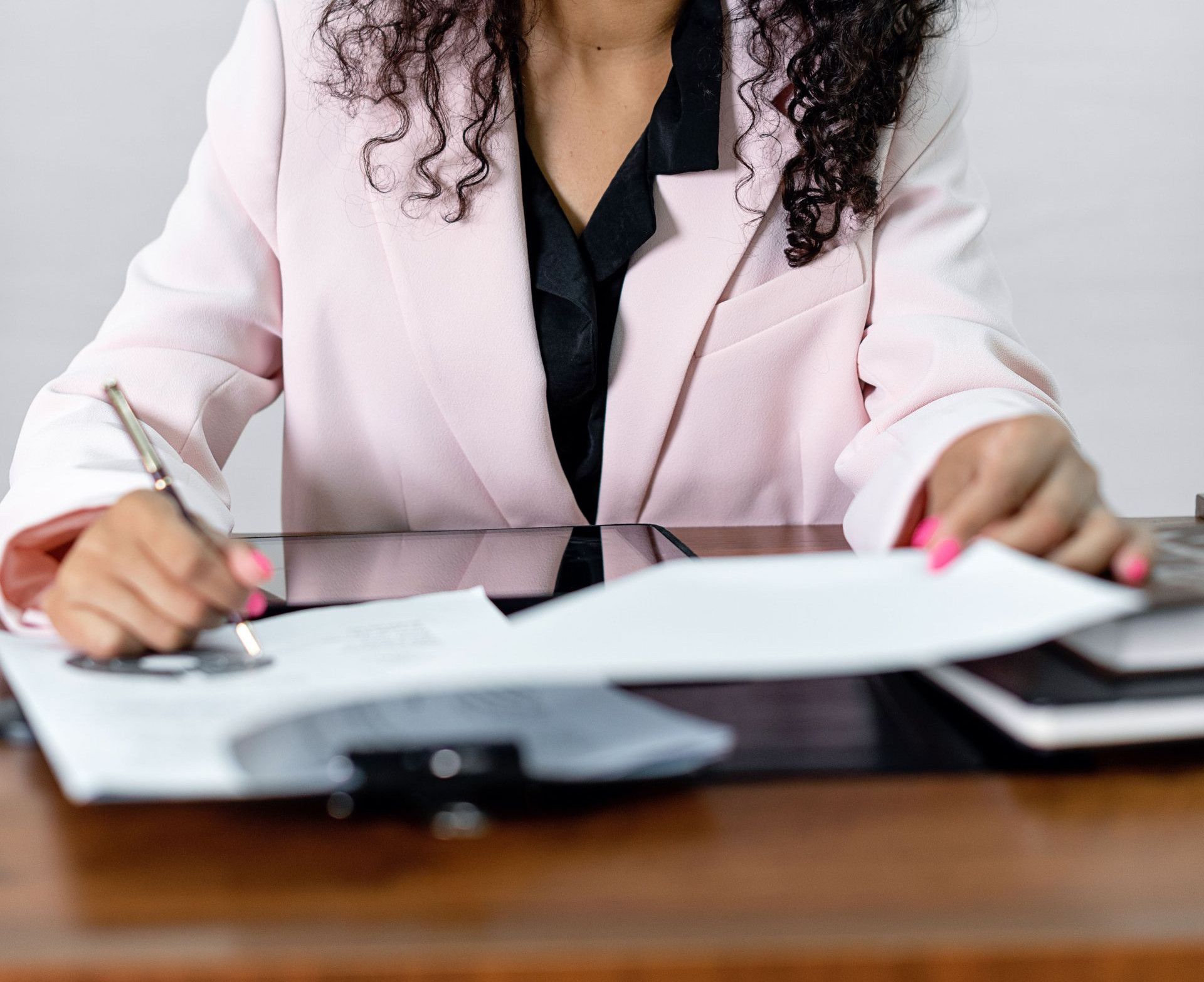 Focused businesswoman signing important documents at her office desk.